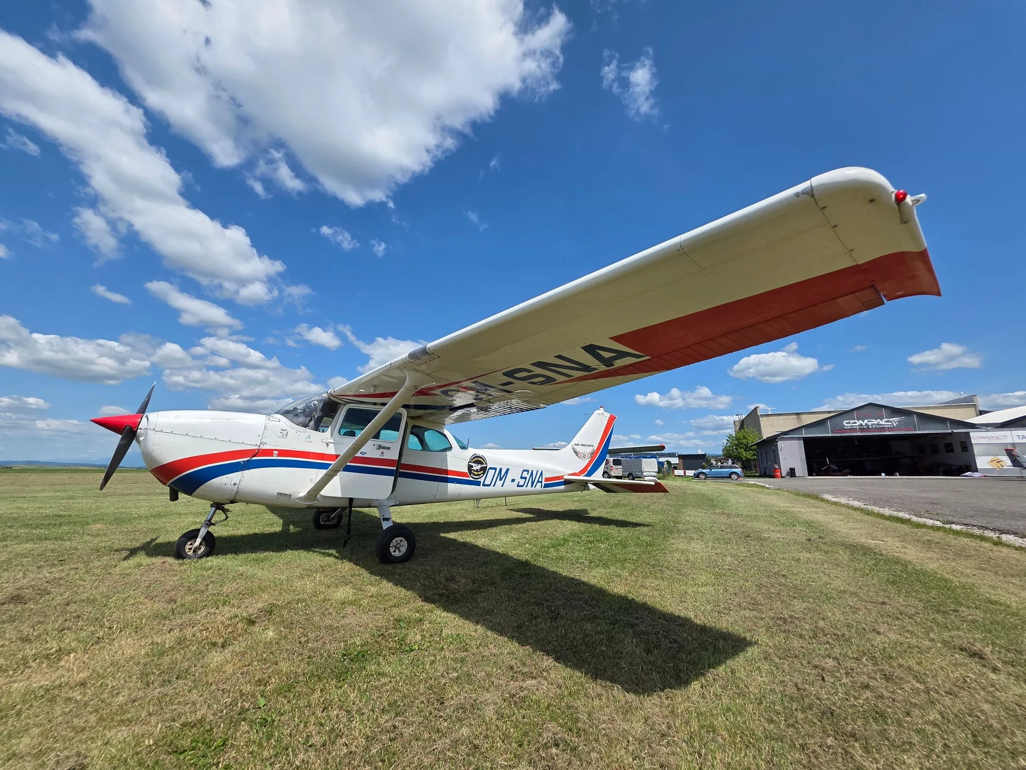 A high-wing training aircraft on a grass airfield